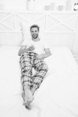 Keyfim yerinde. Tembel pazar hafta sonu evde. Sabah programını izle. Adam televizyon izliyor. Yatakta uzaktan kumandayla kanal değiştir. Uzaktan kumandalı pijamalı mutlu adam. Adam yatak odasında televizyon izliyor.