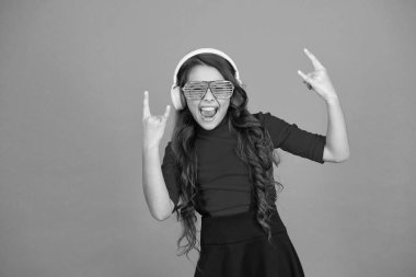 Güzel parça. Parti için çalma listesi. Müzik konsepti. Çocuk gözlük takıyor. Göz giysisi mağazası. Gözlüklü, turuncu arka planda bir kız. Etkinlik ve eğlence. Parti kızı. Parti aksesuarı. Eğleniyorum.