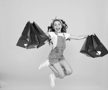 Gerçek mutluluk. Başarılı bir alışveriş yaptıktan sonra mutlu küçük kız. Ağır çantalarla enerjik çocuk atlayışı. Paketlerde bayram hediyeleri. Siber pazartesi. Acele et. Toptan satış. Çocuk modası. Satışlar ve indirimler