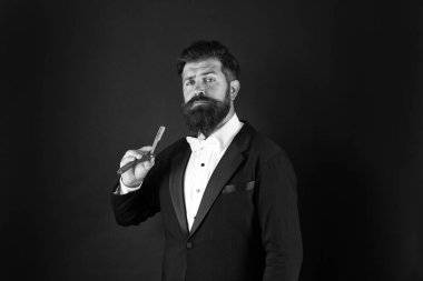 Gerçek bir erkek için gerçek bir tarz. Sakallı adam usturayı düz tut. Uzun bıyıklı ve sakallı profesyonel bir adam. Smokin giymiş acımasız bir adam var. Resmi görünüşlü bir hippi. Berber dükkanı. Kasım ayı yüz kılları için