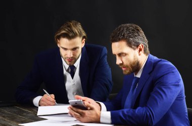 İş ortakları akıllı telefonlara bakar. Destek, başlangıç, finansal anlaşma, teknoloji ve yenilikler kavramı.