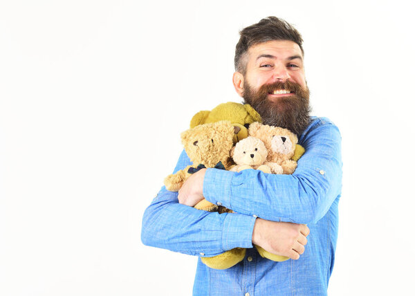 Бородач обнимает много плюшевых мишек. Концепция игрушек и медведей
.