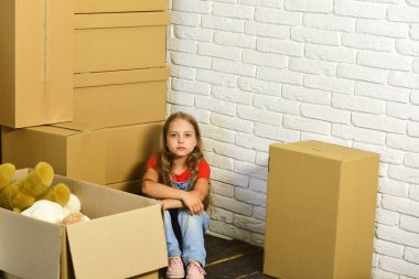 Çocuk köşede yerde oturuyor. Ciddi yüzlü kız.