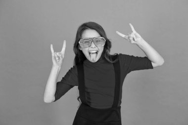 Rock partisi. Maskeli balo konsepti. Çocuk ve çizgili gözlükler. Gözlüklü, turuncu arka planda bir kız. Etkinlik ve eğlence. Parti kutlaması. Gözlük mağazası. Parti aksesuarı. Eğleniyorum.