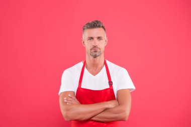 Önlüklü olgun bir adam ellerini çapraz yaptı. Restoranın hostesi. Fast food restoranı. Restoran personeli. Üniformalı adam. Mesleki yaklaşım. Kafemize hoş geldiniz.
