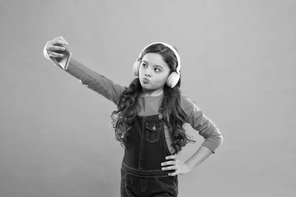 Posando para la foto. chico selfie en los auriculares. videollamada para niños pequeños en smartphone. niña pequeña mantenga el teléfono móvil. bloguear en la vida moderna. colegiala utilizar la nueva tecnología. vivir en el mundo virtual — Foto de Stock