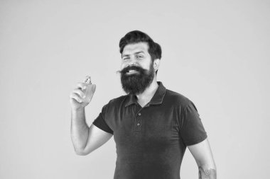 Losyon ve sprey. Parfüm ürünleri konsepti. Sakallı, yakışıklı adam şişe parfümü kullanıyor. Parfüm sürmüş. Erkeklere göre parfüm seç. Gün boyunca taze kokmasını sağla.