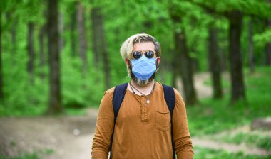 Hava kirliliği yüzünden maske takan bir adam. Adam maske takarak hava kirlenmesinden ya da Coronavirus Covid-19 'dan koruyor. Enfeksiyon. Erkek doğa yürüyüşünden hoşlanır