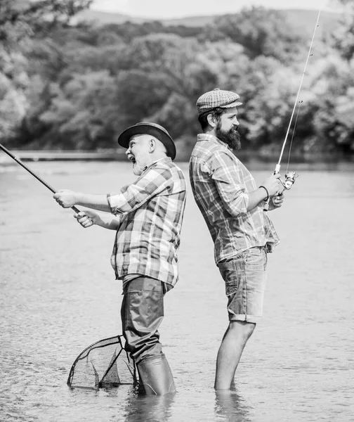 世代です。夏の週末。成熟した男の漁師。男性の友情。家族の絆。趣味とスポーツ活動。トラウト・ベイト。父と息子の釣り。釣竿と網を持った2人の幸せな漁師が — ストック写真