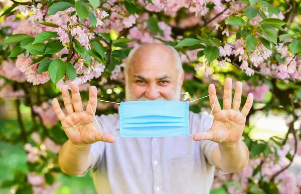 Senior man face mask. Respiratory mask. Pollen allergen. Man and flowers. Allergic reaction. Limit risk infection spreading. Respiratory condition. Asthma treatment concept. Difficulty in breathing