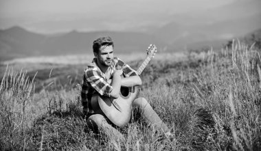 Seyahat tutkusu konsepti. İlham verici bir doğa. Yaz tatili doğada var. İlham arayan bir müzisyen. Hayalperest gezgin. Tek başına iyi vakit geçirdin. Huzurlu bir ruh hali. Gitarlı adam doğayı düşünüyor.