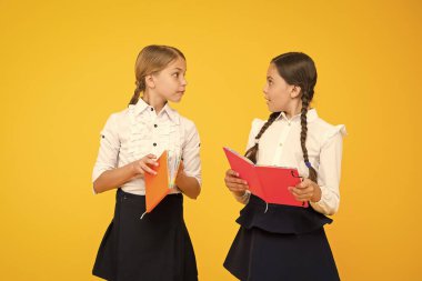 Dil eğitimi. Sevimli çocuklar ders kitabı ile çalışır. Okul çalışmaları için okuma becerilerini pratik edin ve geliştirin. Okul konseptine geri dönelim. Kızlar kitap tutar. Kız öğrenciler sarı arka plan üzerinde birlikte çalışma