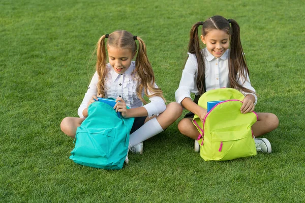 Haciendo mejor los deberes al aire libre. Los niños pequeños hacen los deberes en la hierba verde. Las niñas recogen el diario de la tarea de la bolsa. Asignación de tareas. Enseñanza en casa. Clases privadas. Escuela y educación — Foto de Stock