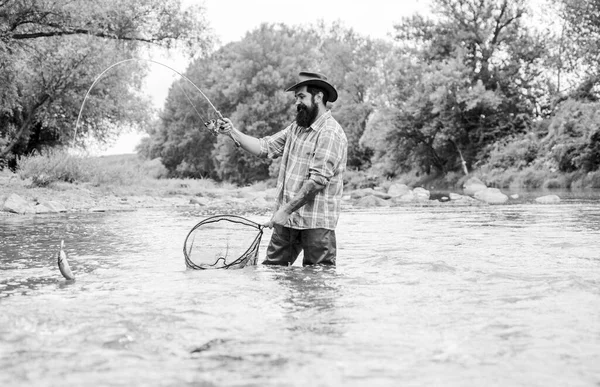 Fishing is astonishing accessible recreational outdoor sport. Fishing hobby. Fishing provides that connection with whole living world. Find peace of mind. Bearded fisher catching trout fish with net
