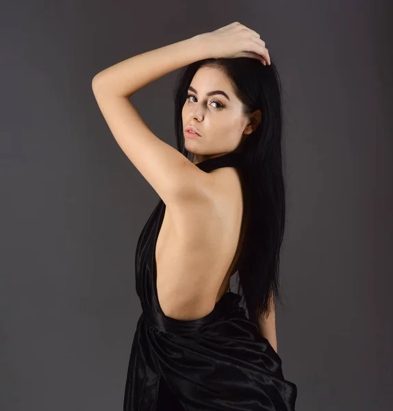 Lady, confident sexy girl in dress. Attractive girl wears expensive fashionable evening dress with nude shoulders. Woman in elegant black dress with naked back, dark background. Desire concept — Stock Photo, Image