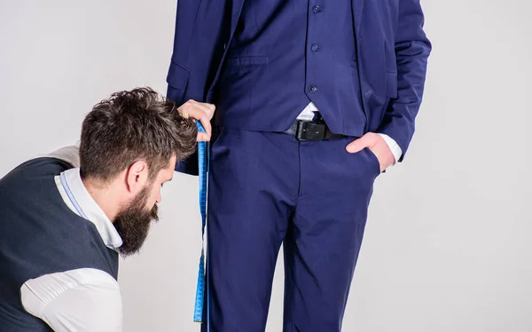 Tailor měří délku nohy, pro šití kalhot, bílé pozadí. — Stock fotografie