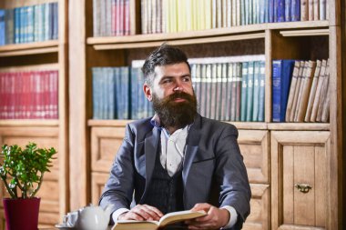 Gülen surattaki aristokrat kitabı tutuyor. Klasik takım elbiseli adam.