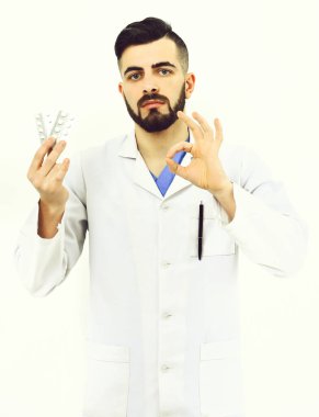 Sakallı doktor hapları tutuyor ve tamam işareti gösteriyor.