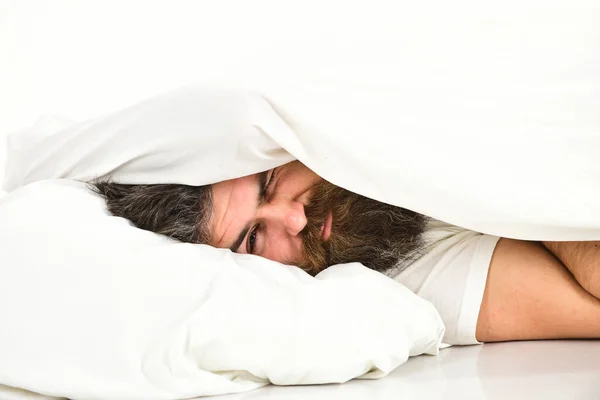 Guy with beard hides face under blanket.