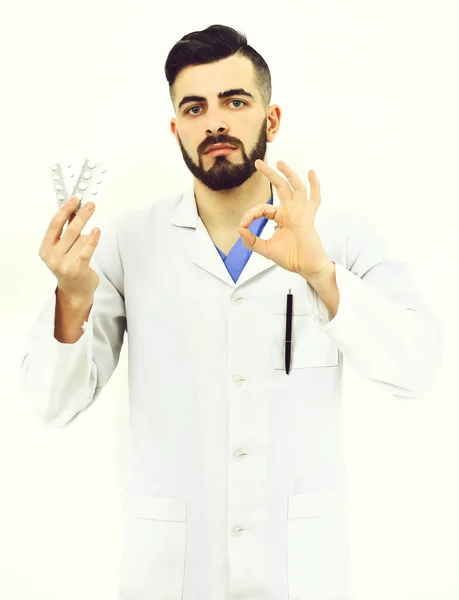 Doctor with beard holds pills blisters and shows ok sign — Stock Photo, Image