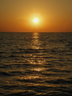 Turuncu tonlarda denizin üzerinde gün batımı.