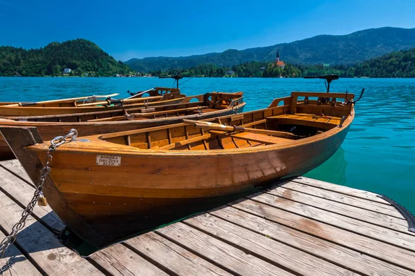 澄んだ青い湖の上に木製のボートが出血した 澄んだアクアマリン水 観光船 湖と劇的な青い空 — ストック写真