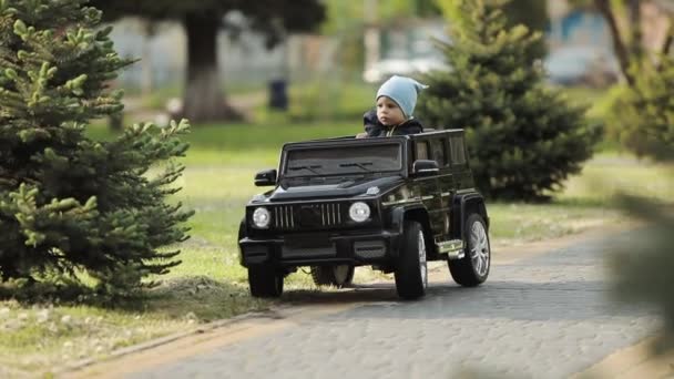 Anak itu mengendarai mobil anak-anak. Warna hitam ungu. Anak kecil mengemudi dengan mobil mainan listrik.. — Stok Video