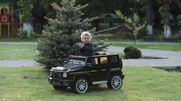 웃는 아이가 장난감 차에 앉아 손을 박수를 치는 모습. — 비디오