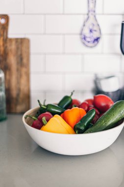 Bambu kasesinde renkli sebzeler. Çiftlik hasadı. Ev bahçesi. Evde bahçıvanlık. Biberler, bahçeden domatesler. Sebzelerin üzerine su damlası. Temiz yemek. Mutfak lavabosu ve masa..