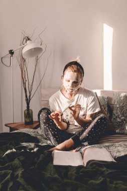 Yatakta maske takan genç bir bayan. Kız güzelliği rutini. Kişisel bakım tedavisi. Günlük rutin. Çivilerin umurunda. Yatak odasında pijama partisi. Güzel bayan. Sağlık ve güzellik hizmetleri. Sonsuza dek genç. Rahat.