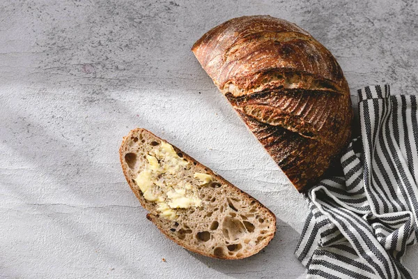 Authentic sourdough bread. Leavened bread. Sourdough starter. Whole wheat bread. Homemade. Piece of bread. Salted butter. Rustic organic bio product. Handcrafted product. Grey white backdrop. Slice