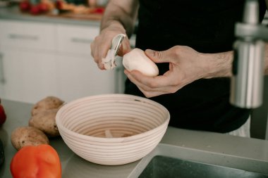 Yemek hazırlama. Patates soymak. Patates kabuğu. Mutfak tezgahı. Mutfak lavabosu. Yemek hazırlıyorum. Adam akşam yemeği pişiriyor. Koca akşam yemeği pişirmeye yardım eder. Soyucu aletleri. Yaşam tarzı mutfak. Yiyecek atıkları. Sebze