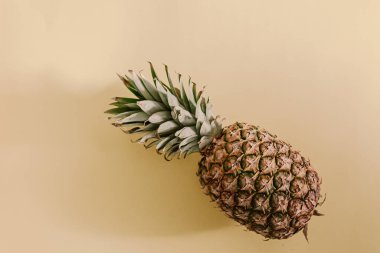 Minimalist sarı fon, ananas meyvesi. Parlak renkli içerik. Kağıt arkaplan. Tropik egzotik meyve. Turuncu renk, sarı. Renk belirdi. Sert ışık, yumuşak gölgeler. Doğrudan güneş ışığı. Gölgeler
