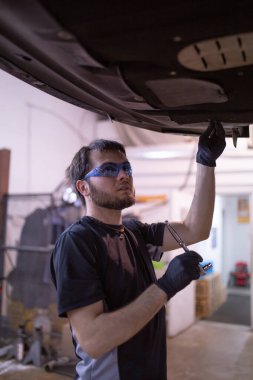 Araba tamiri servisi. Yağ değişimi. Otomobil servisi. Tamirci çalışıyor. Araba tamircisi. Otomobil bakımı. Araç parçası değiştirme. Tamirci arabadaki motoru inceliyor. Araba tamiri. Araba kaldırıldı.