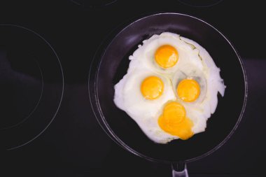 Kızartma tavasında yumurta. Dört yumurta. Aileye kahvaltı hazırlıyorum. Aile kahvaltısı. Hızlı, kolay bir kahvaltı. Orta pişmiş yumurta. Yumurta sarısı, yumurta beyazı. Siyah sobanın üstü. Kırık yumurta sarısı