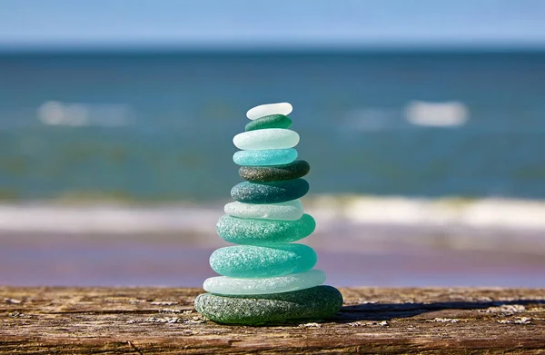 Balance of stones. Glass stones on a wooden table against the sea