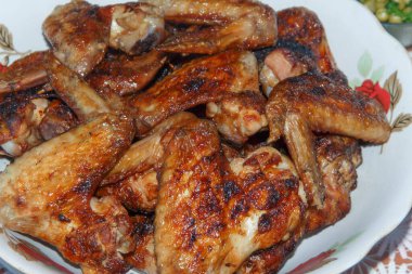 Yanan tavuk kanatlarıyla dolu bir tabak, yakın plan.