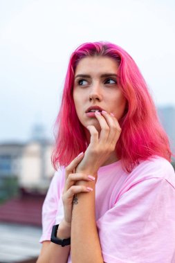 Çatıda pembe saçlı bir kızın portresi.