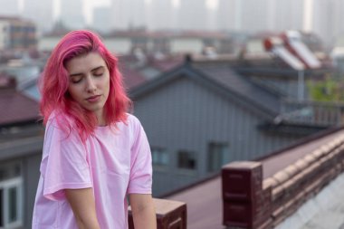 Çatıda pembe saçlı bir kızın portresi.