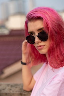 Gözlüklü, pembe saçlı bir kızın portresi.