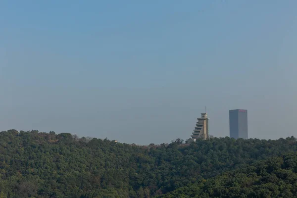 view of two skyscrapers over hill on blue sky background