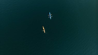 Kanolar içinde yüzen insanların havadan görünüşü. 