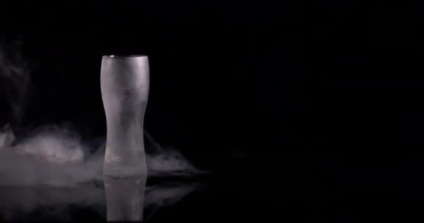 スローモーションで黒を背景に煙の中にガラスを逃した ビールのグラス — ストック動画