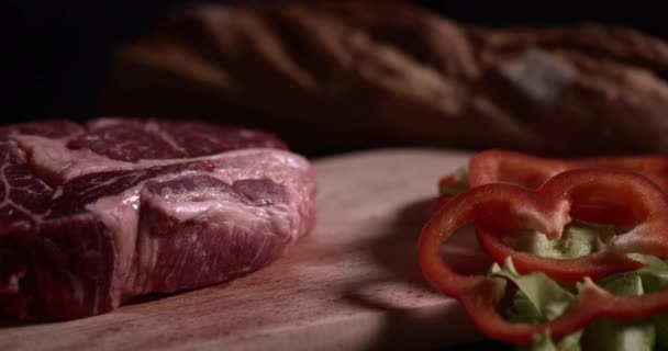 Syrový Steak Olejem Zeleninou Leží Dřevěné Desce Černém Pozadí Zpomaleném — Stock video