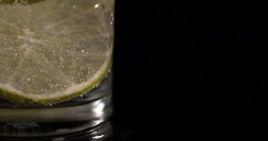 limonlu soda ve baloncuklu limon ve siyah arka planda buz. Camda limonata 