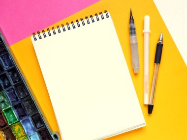 Beyaz, sarı ve pembe kağıt arka planda boş not defteri ve çizim araçları içeren şablon.