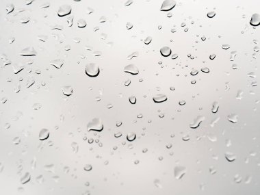 Pencereye, havaya, arka plandaki su damlalarına şeffaf yağmur damlalarına bastırılacak gri arkaplan / yağmur damlaları