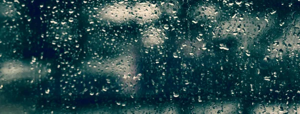 Gocce piovose sul vetro con lo sfondo blu scuro sfocato — Foto Stock