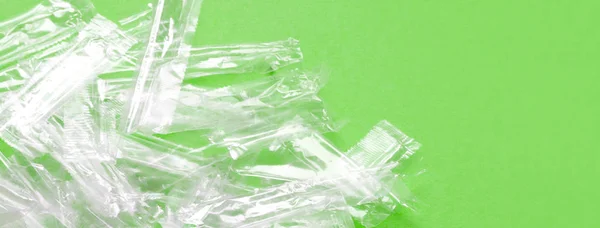 緑の背景に透明なプラスチック包装廃棄物の山. — ストック写真