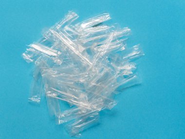 Mavi arka planda şeffaf plastik ambalaj çöpü yığını.